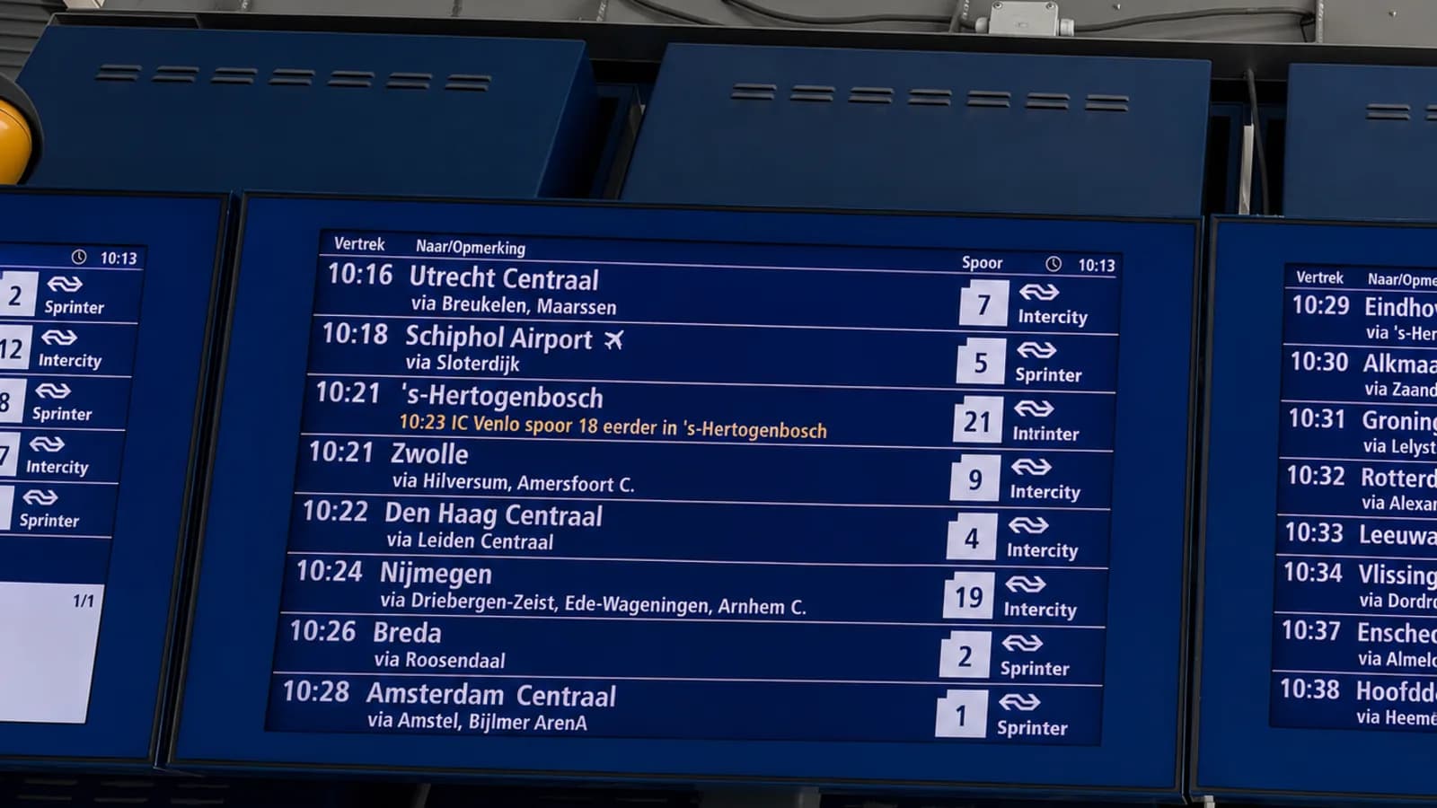 Blauwe vertrekschermen boven een perron met vertrektijden, bestemmingen en spoornummers